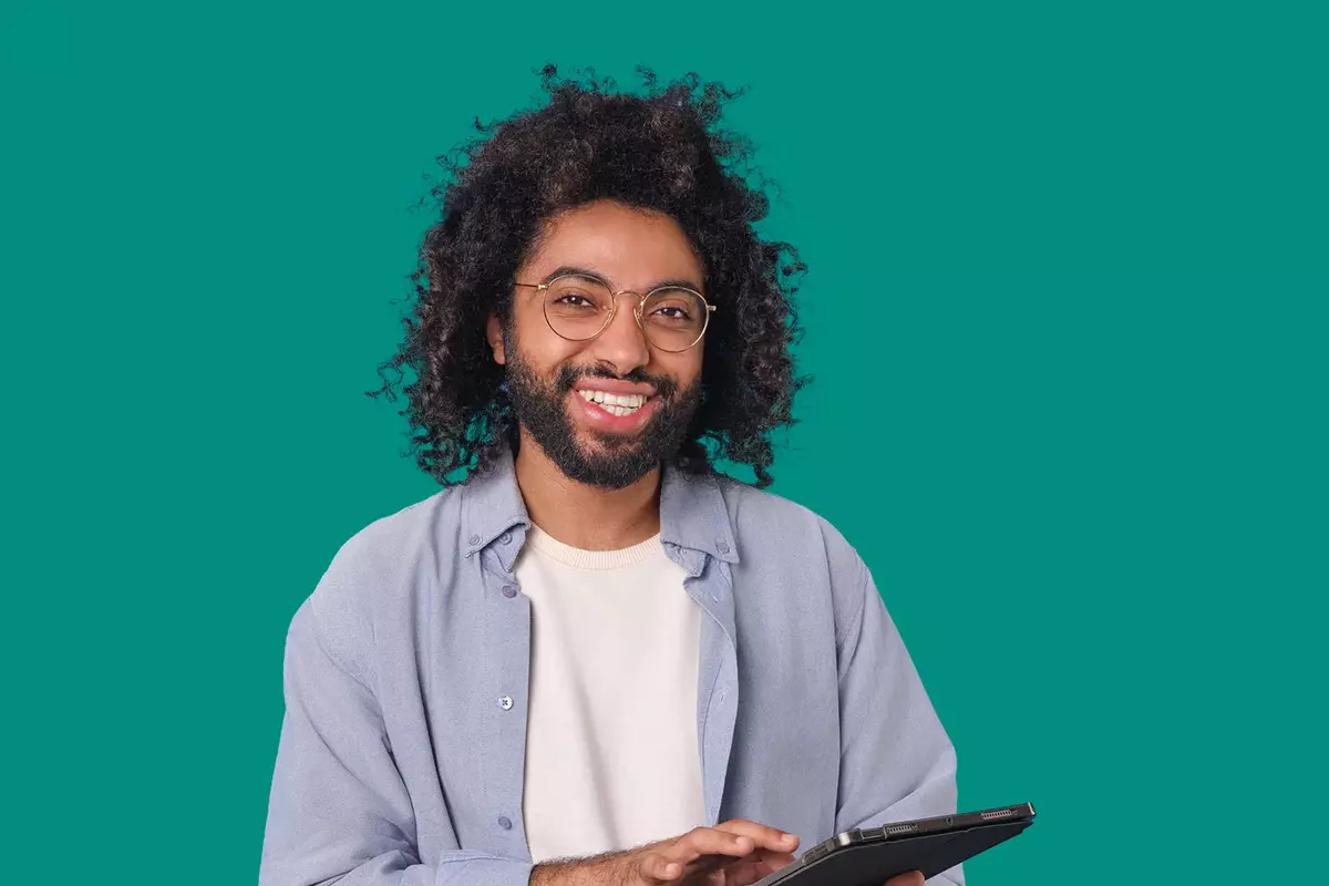 Junger Mann mit Brille und Tablet in der Hand vor grünem Hintergrund