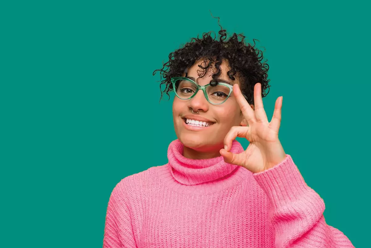 Junge Frau mit pinkem Shirt und Brille vor grünem Hintergrund