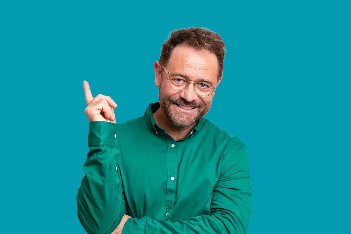 Mann zeigt, mit grünem Hemd vor blauem Hintergrund