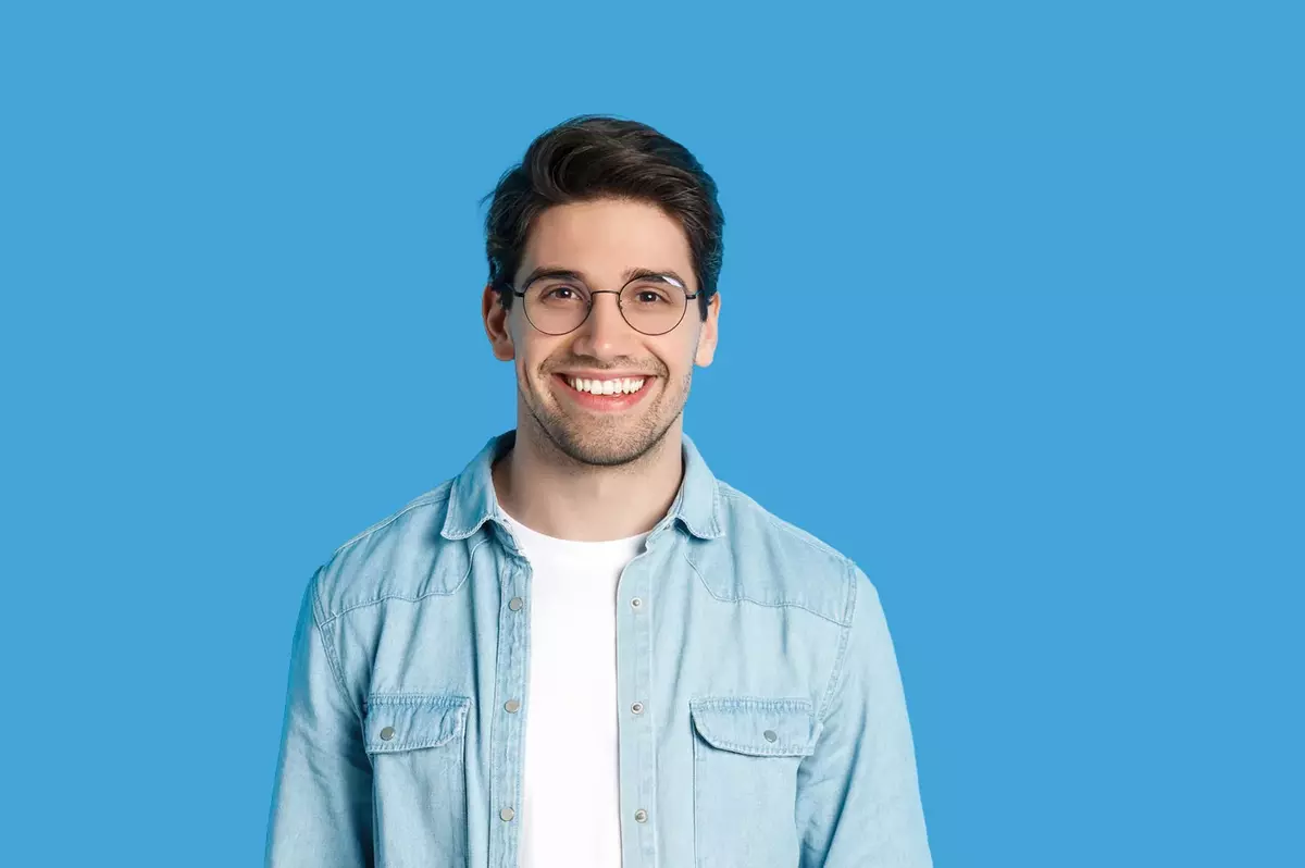 Junger Mann mit Brille vor hellblauem Hintergrund